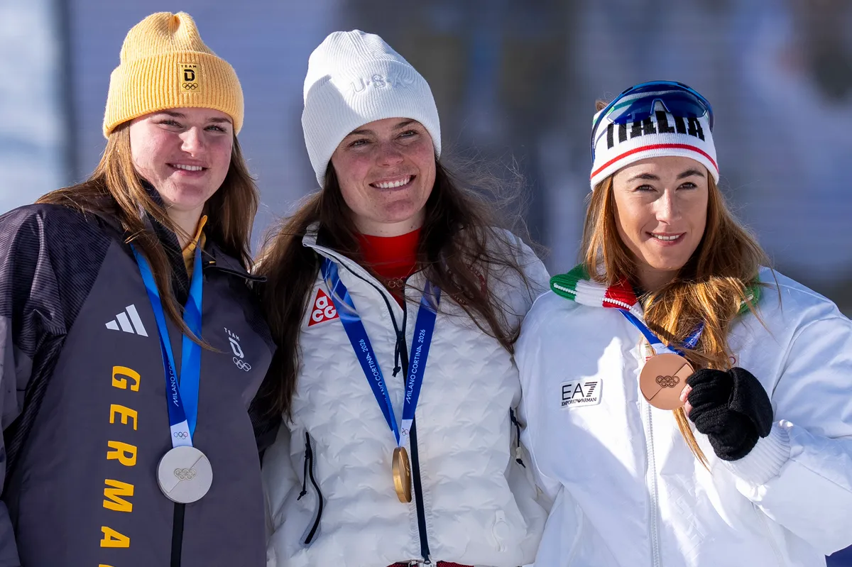 Emma Aicher (német ezüstérmes), Breezy Johnson (amerikai aranyérmes) és Sofia Goggia (olasz bronzérmes) a női lesiklás eredményhirdetése után pózolnak a milánói–cortinai téli olimpia második napján – Johnson ekkor még sértetlenül viselte a később megsérült aranyérmét. Fotó: ANDRZEJ IWANCZUK / NurPhoto