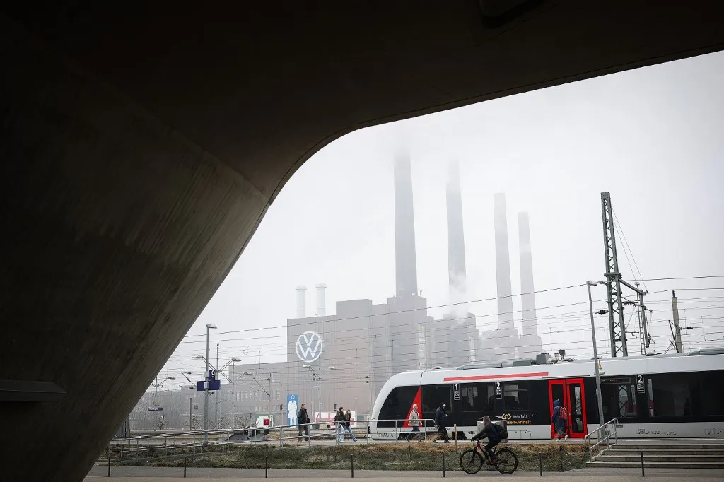 A RB (Regional railway) train stands during misty weather at the main railway station in front of the power plant of the headquarters of German carmaker Volkswagen (VW) in Wolfsburg, central Germany, on March 11, 2025. (Photo by Ronny HARTMANN / AFP), Elég ködösnek tűnik a Volkswagen jövője mostanában
