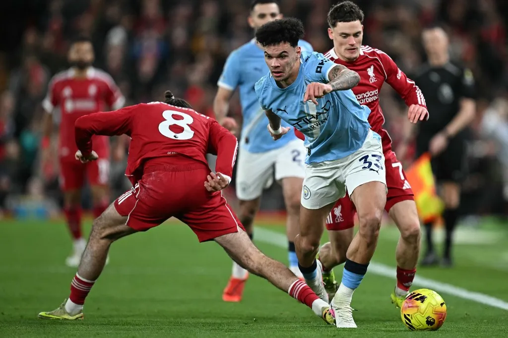 Manchester City's English midfielder #33 Nico O'Reilly (C) is challenged by Liverpool's Hungarian midfielder #08 Dominik Szoboszlai (L) during the English Premier League football match between Liverpool and Manchester City at Anfield in Liverpool, north west England on February 8, 2026. (Photo by Paul ELLIS / AFP) / RESTRICTED TO EDITORIAL USE. No use with unauthorized audio, video, data, fixture lists, club/league logos or 'live' services. Online in-match use limited to 120 images. An additional 40 images may be used in extra time. No video emulation. Social media in-match use limited to 120 images. An additional 40 images may be used in extra time. No use in betting publications, games or single club/league/player publications. /