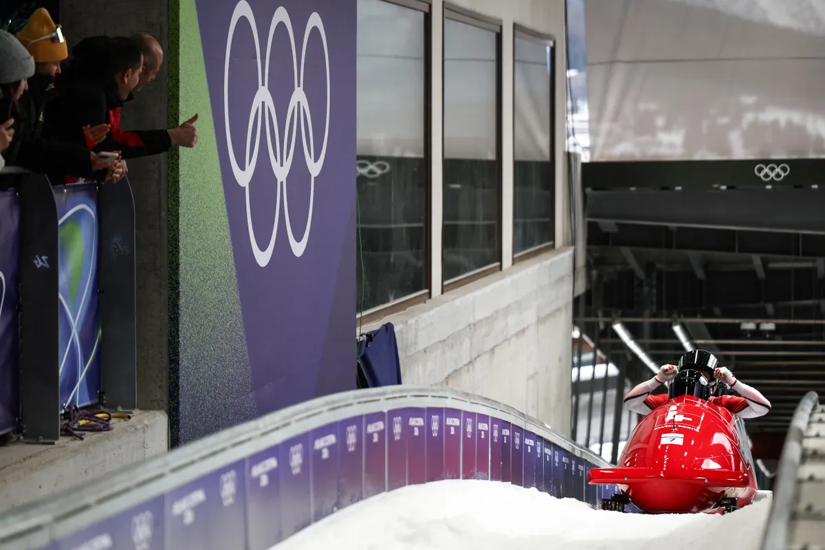 Switzerland's Michael Vogt, Switzerland's Andreas Haas, Switzerland's Amadou David Ndiaye and Switzerland's Mario Aeberhard react after crossing the finish line in the bobsleigh men's 4-man heat 4 at Cortina Sliding Centre during the Milano Cortina 2026 Winter Olympic Games in Cortina d'Ampezzo on February 22, 2026. (Photo by FRANCK FIFE / AFP)