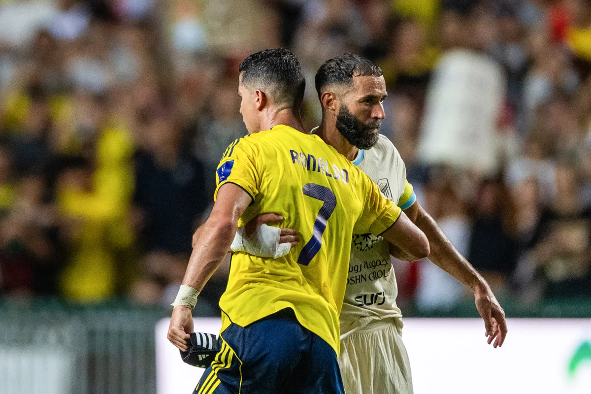 Al-Nassr's Cristiano Ronaldo (L) embraces Al-Ittihad's Karim Benzema during the Saudi Super Cup semi-final football match between Al-Nassr and Al-Ittihad at the Hong Kong Stadium in Hong Kong on August 19, 2025. (Photo by Wun Suen / AFP)