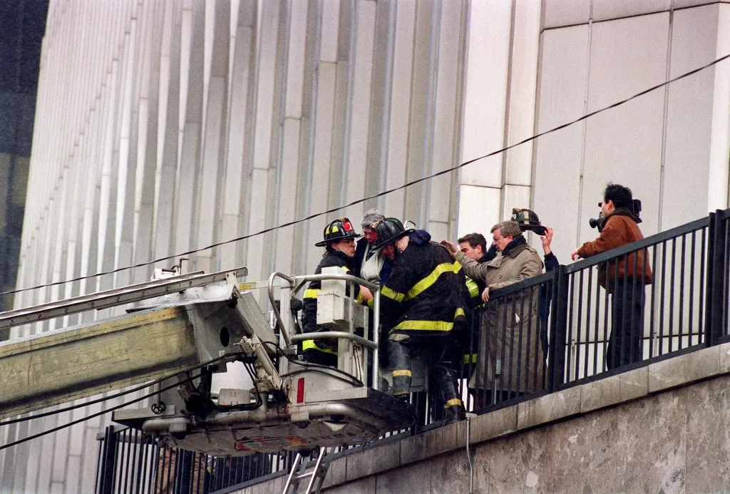 Fireman lower a women down from the World Trade Center plaza onto a ladder truck after smoke swept through the 110-story building after a ceiling of a train station collapsed 26 feb setting off a fire below the twin towers. (Photo by MARIA BASTONE / AFP)