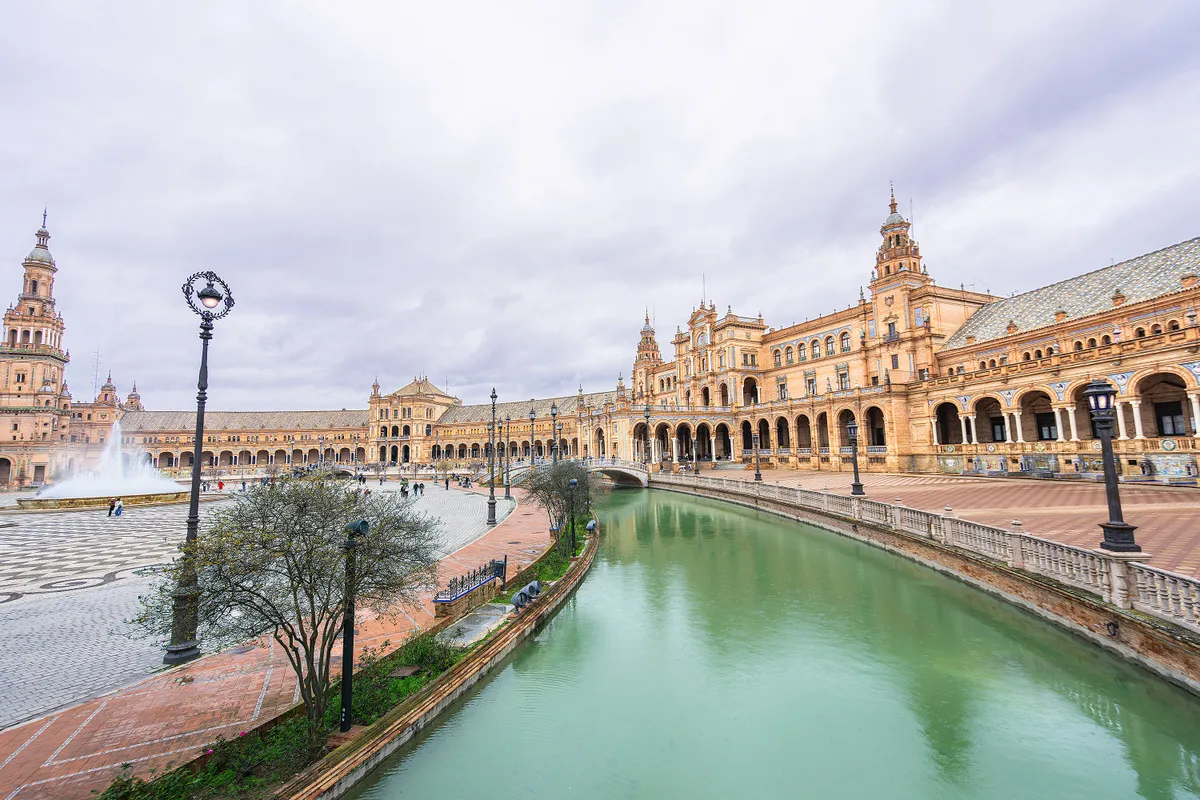 Sevilla, Spain - March 10, 2025: Spanish square with canal and ornate towers. Baroque, Renaissance, and Moorish architecture blend in the design. Features a 500 meter waterway.