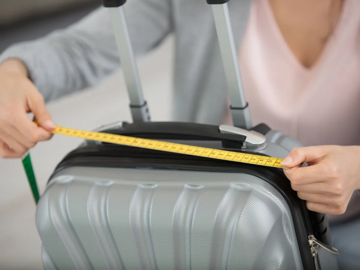 woman measuring suitcase before travel