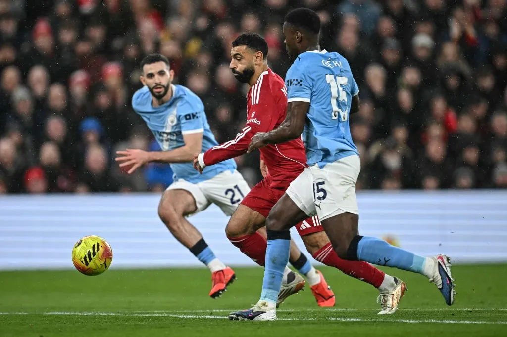 Manchester City's Allgerian defender #21 Rayan Ait-Nouri (L) and Manchester City's English defender #15 Marc Guehi (R) challenge Liverpool's Egyptian striker #11 Mohamed Salah (C) during the English Premier League football match between Liverpool and Manchester City at Anfield in Liverpool, north west England on February 8, 2026. (Photo by Paul ELLIS / AFP) / RESTRICTED TO EDITORIAL USE. No use with unauthorized audio, video, data, fixture lists, club/league logos or 'live' services. Online in-match use limited to 120 images. An additional 40 images may be used in extra time. No video emulation. Social media in-match use limited to 120 images. An additional 40 images may be used in extra time. No use in betting publications, games or single club/league/player publications. /