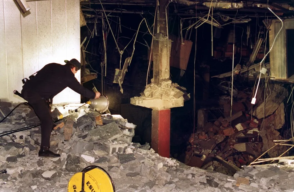 A police photographer adjusts a light at the edge of the crater in an underground parking garage at the World Trade Center 28 February 1993. The explosion killed 05 people and injured over 1,000. AFP PHOTO MARK D. PHILLIPS (Photo by Mark D. PHILLIPS / AFP)