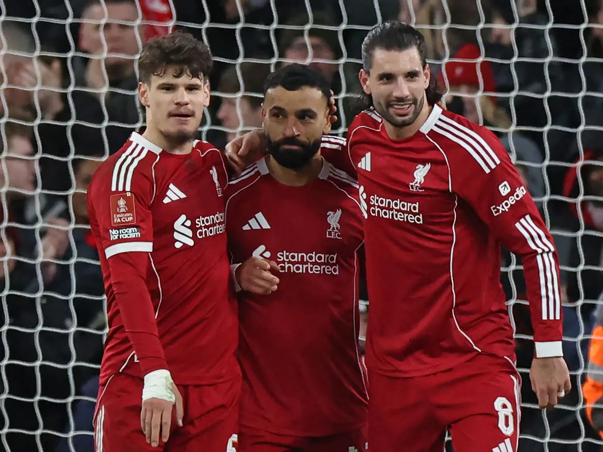 Liverpool's Egyptian striker #11 Mohamed Salah (C) celebrates with Liverpool's Hungarian defender #06 Milos Kerkez (L) and Liverpool's Hungarian midfielder #08 Dominik Szoboszlai (R) after scoring their third goal from the penalty spot during the English FA Cup fourth round football match between Liverpool and Brighton and Hove Albion at Anfield in Liverpool, north west England on February 14, 2026. (Photo by Darren Staples / AFP) / RESTRICTED TO EDITORIAL USE. No use with unauthorized audio, video, data, fixture lists, club/league logos or 'live' services. Online in-match use limited to 120 images. An additional 40 images may be used in extra time. No video emulation. Social media in-match use limited to 120 images. An additional 40 images may be used in extra time. No use in betting publications, games or single club/league/player publications. / 