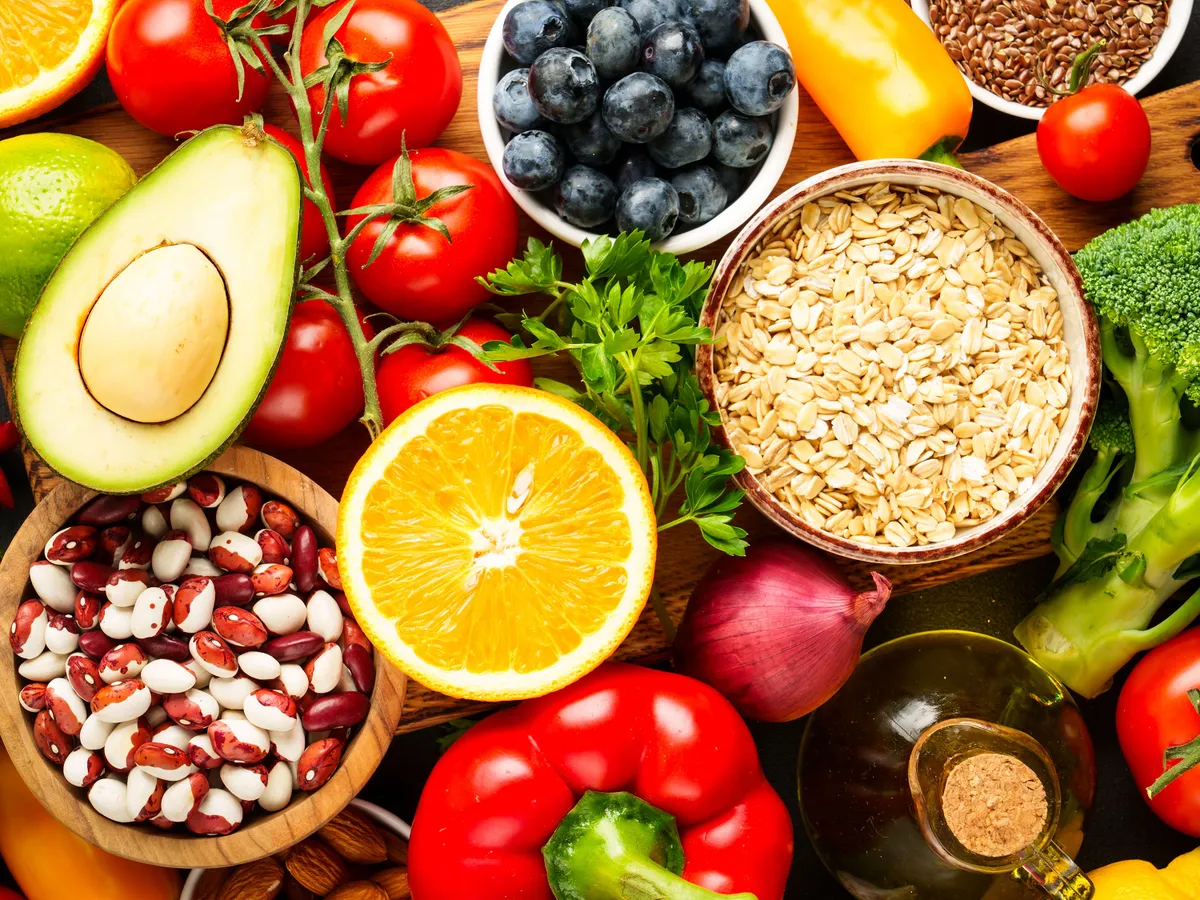 Healthy food assortment on black background. Fresh vegetable, grains, leaves and nuts. Top view.