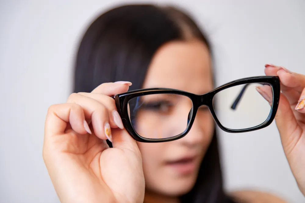 Modern eyeglasses with a black frame in woman's hands. Eye care and the choice the means to improve vision. Macro shot.