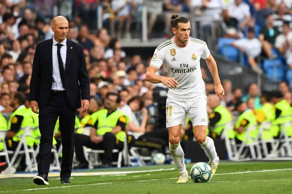 Real Madrid's French coach Zinedine Zidane (L) looks at Real Madrid's Welsh forward Gareth Bale (R) during the Spanish League football match between Real Madrid and Real Valladolid at the Santiago Bernabeu stadium in Madrid on August 24, 2019. (Photo by GABRIEL BOUYS / AFP)