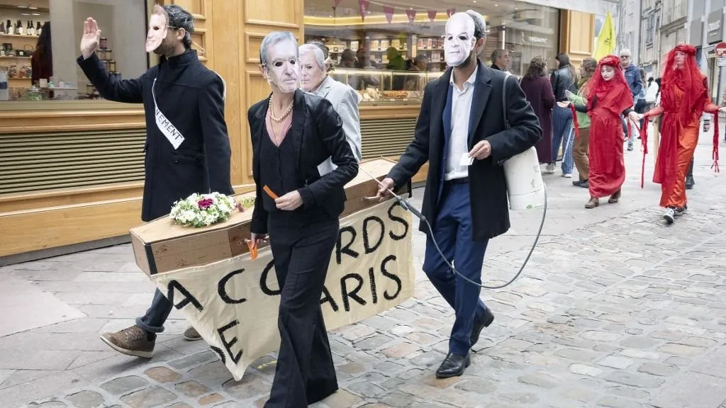 klímaszorongás France, Poitiers, 11 October 2025. In response to the climate emergency, activists from the Extinction Rebellion (XR) movement walk through the streets of the city carrying a coffin to symbolise the burial of the Paris Agreement. They wear the masks of those they consider to be primarily responsible for this failure: Bernard Arnault, Vincent Bollore, Emmanuel Macron and Marc Fesneau. Behind the coffin walk two Red Rebels, young women dressed in red, symbolising the blood of slaughtered animals. One of the demonstrators, wearing the mask of agro-industrialist Arnaud Rousseau, carries a pesticide sprayer on his back. Photograph by Jean-Francois Fort / Hans Lucas.
France, Poitiers, 2025-10-11. Devant l urgence climatique, des activistes du mouvement Extinction Rebellion (XR) deambulent dans les rues de la ville en portant un cercueil symbolisant l enterrement des accords de Paris. Ils portent les masques de ceux qu ils estiment les principaux responsables de cet echec : Bernard Arnault, Vincent Bollore, Emmanuel Macron, Marc Fesneau. Derriere le cercueil marchent deux Red Rebels, jeunes femmes vetues de rouge, symbolisant le sang des animaux tues. Un des manifestants portant le masque de l agro industriel Arnaud Rousseau, porte sur son dos un pulverisateur de pesticides. Photographie de Jean-Francois Fort / Hans Lucas. (Photo by Jean-François FORT / Hans Lucas via AFP)