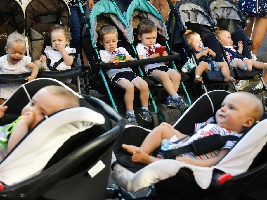 gyerekszám Twins and triplets sit in their stroller as they arrive for the children's Festival Of Twins, in Kiev, on August 11, 2018. Representatives of the Ukrainian Records Book set the new country's record at more than 200 pairs of twins and triplets during the event. (Photo by Sergei SUPINSKY / AFP)