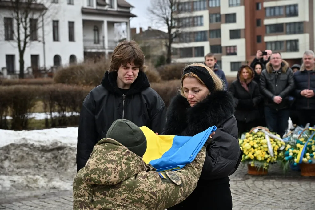 LVIV, UKRAINE - FEBRUARY 24: Soldiers, citizens and relatives of the Ukrainian soldiers, who died in the Russian-Ukrainian war, attend the funeral ceremony at Lychakiv Cemetery in Lviv, Ukraine on February 24, 2026. On the fourth anniversary of Russia's full-scale invasion of Ukraine, the city bid farewell to three soldiers who died in the war. Michael Sorrow / Anadolu (Photo by Michael Sorrow / Anadolu via AFP)