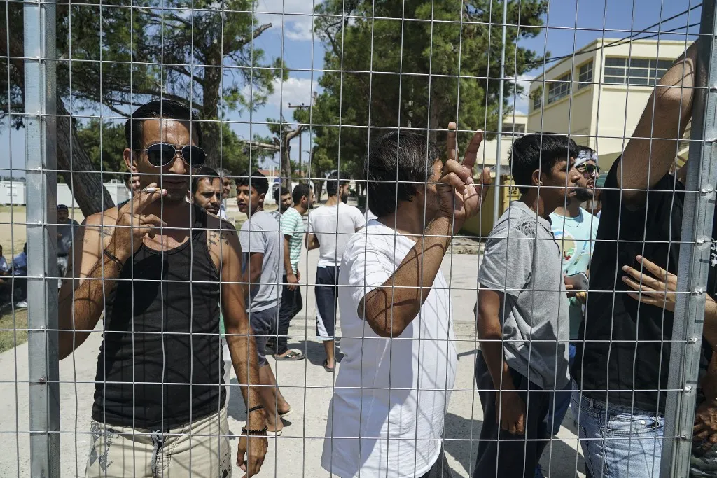Refugees are protesting in Diavata Camp (Former Anagnostopoulou military camp), in Thessaloniki, Greece, on August 17, 2017. They blocked the entrance and rushed out all the government and  ngo employees including army and police. Refugees and migrants are from Syria, Iran, Afghanistan, Pakistan and Kurdish in this camp. They are protesting because in the transformed house containers that they live, more people will come. The camp hosts about 350 people with AC, kitchen, WC in each container and the number of the guests can be expanded at least for more 20%. The government is bringing , actually relocation from camps in bad conditions from the islands, 27 people by bus to this camp. Each container house can host 6 people. For the moment in most of the houses live 4 people. Refugees even denied to reunite their families that hold two containers. The ministry arranged a few empty containers but refugees and migrants still keep protesting. Other demands from the refugees are to leave the camp and live in house, relocate to European countries like Germany and organize a school in the camp for little children. Local authorities and police are blocked outside of the camp. The temperature in the camp is about  36°C right now and they still stay outside.  (Photo by Nicolas Economou/NurPhoto) (Photo by Nicolas Economou / NurPhoto via AFP)