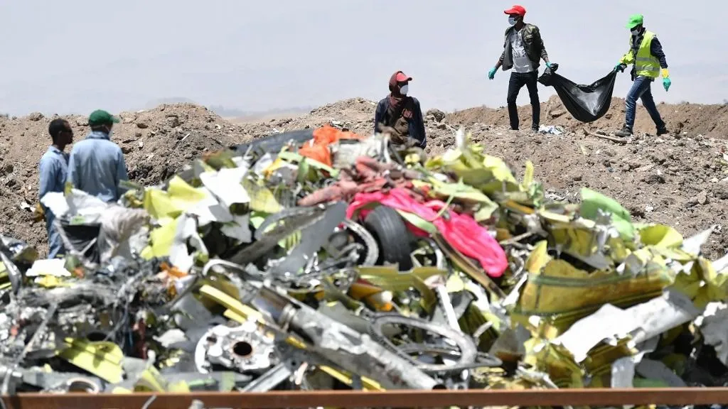 A crew working with an investigative team to clear the site after the Sunday crash of the Ethiopian Airlines operated Boeing 737 MAX aircraft, carry debris at Hama Quntushele village in the Oromia region, on March 13, 2019. A Nairobi-bound Ethiopian Airlines Boeing crashed minutes after takeoff from Addis Ababa on March 10, killing all eight crew and 149 passengers on board, including tourists, business travellers, and "at least a dozen" UN staff. Families of the victims were taken to the remote site on March 13, 2019, where the plane smashed into a field with 157 passengers and crew from 35 countries, leaving a deep black crater and tiny scraps of debris. (Photo by TONY KARUMBA / AFP)