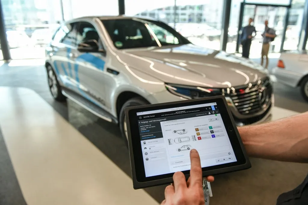 23 August 2019, Berlin: ILLUSTRATION - A service employee holds a tablet in the newly built service terminal in the Berlin Mercedes world at Salzufer during a service check of the electric SUV Mercedes EQC 400. (Presented scene.) The new service lounge is completely geared to the requirements of electric mobility. Photo: Jens Kalaene/dpa-Zentralbild/ZB (Photo by JENS KALAENE / dpa-Zentralbild / dpa Picture-Alliance via AFP)