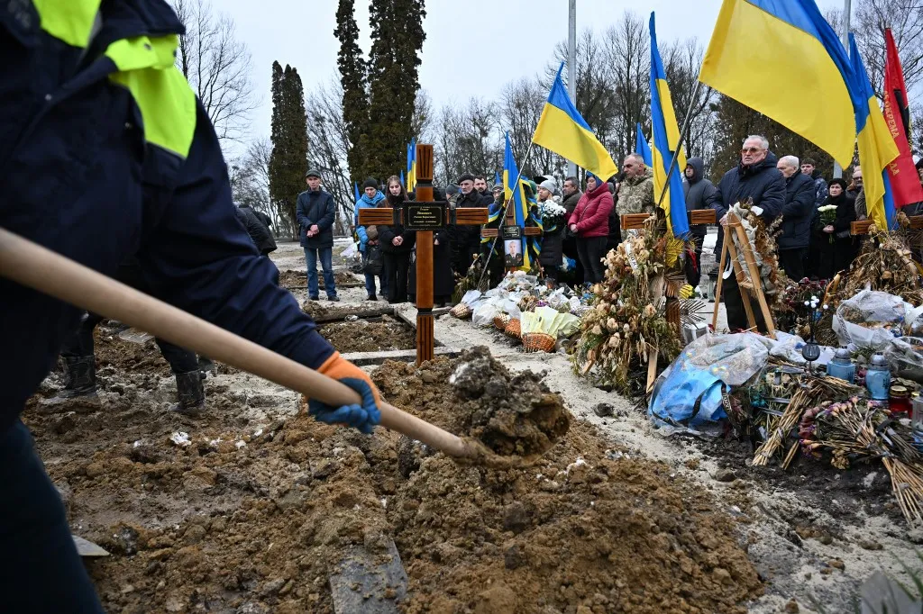 LVIV, UKRAINE - FEBRUARY 24: Soldiers, citizens and relatives of the Ukrainian soldiers, who died in the Russian-Ukrainian war, attend the funeral ceremony at Lychakiv Cemetery in Lviv, Ukraine on February 24, 2026. On the fourth anniversary of Russia's full-scale invasion of Ukraine, the city bid farewell to three soldiers who died in the war. Michael Sorrow / Anadolu (Photo by Michael Sorrow / Anadolu via AFP)