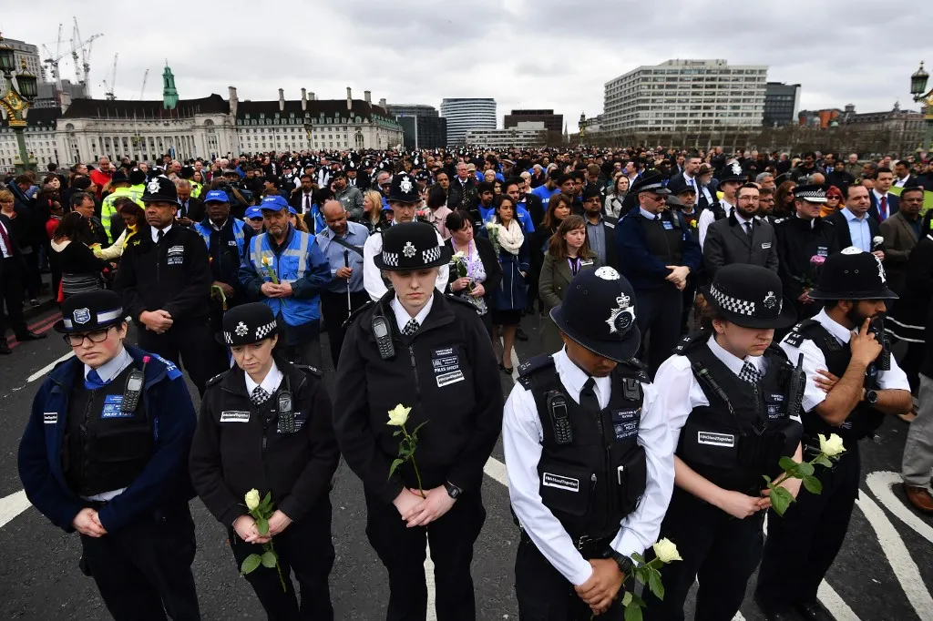 Members of the police force hold white roses as they join members of the public on Westminster Bridge in central London on March 29, 2017 for a vigil to commemorate one-week since the March 22 terror attack that killed four. Four people were killed and scores more injured after British man Khalid Masood ploughed a speeding vehicle through a crowd of pedestrians and fatally stabbed a policeman just inside the gates of the British parliament before being shot dead himself in a frenzied attack lasting just 82 seconds on March 22. (Photo by BEN STANSALL / AFP)