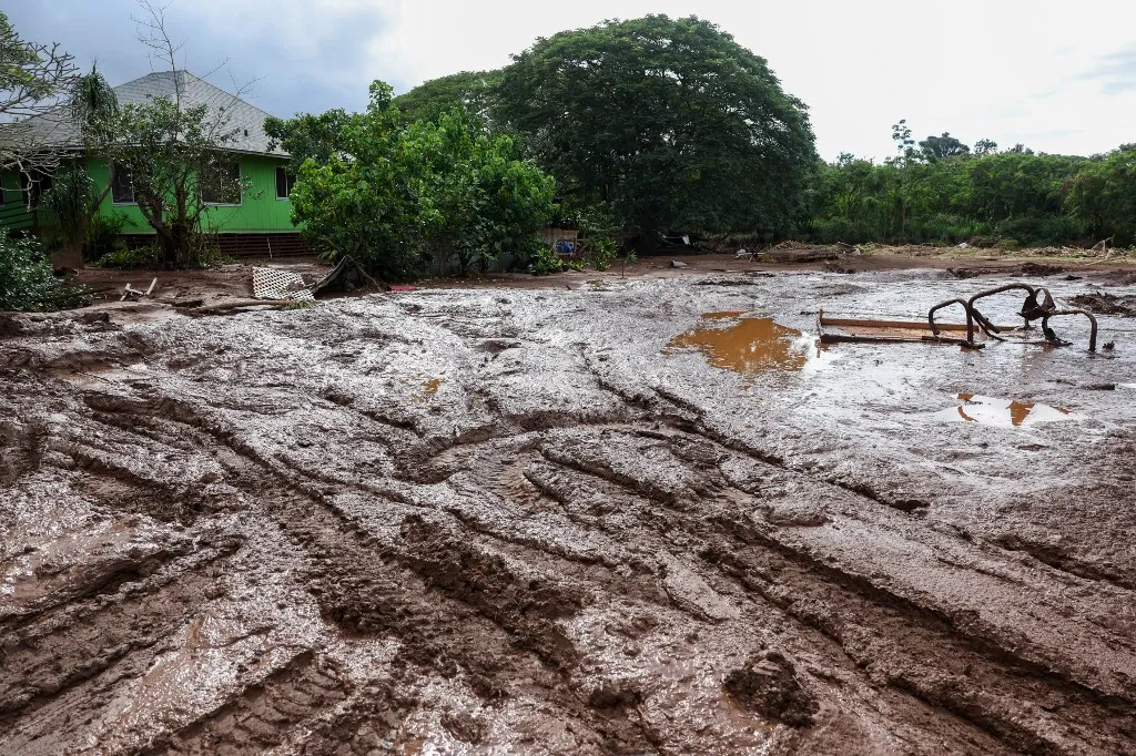 Thick mud and debris surround a home after the Kona Low storm flood devastated the Otake Camp community in Waialua, Hawaii on March 22, 2026. Severe rains have battered the region over the weekend prompting officials to order evacuations. (Photo by Marco GARCIA / AFP)