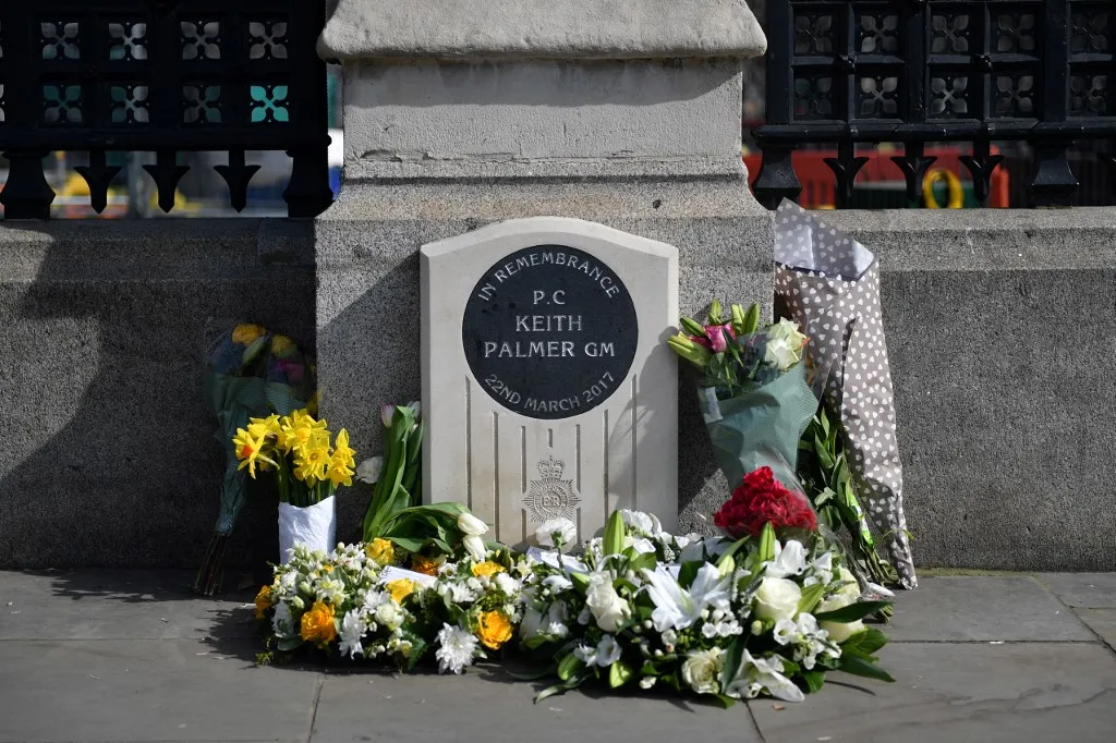 A photograph taken on March 22, 2022, by the Houses of Parliament, in London shows wreathes of flowers placed by a memorial plaque to mark the fifth anniversary of the death of PC Keith Palmer, who was murdered during a terrorist attack of March 22, 2017. PC Keith Palmer was fatally stabbed as he stood guard in front of Britain's Houses of Parliament in Westminster on March 22, 2017 by Khalid Masood after the 52 year-old convert to Islam drove into pedestrians at high speed near parliament, killing four other people. (Photo by JUSTIN TALLIS / AFP)
