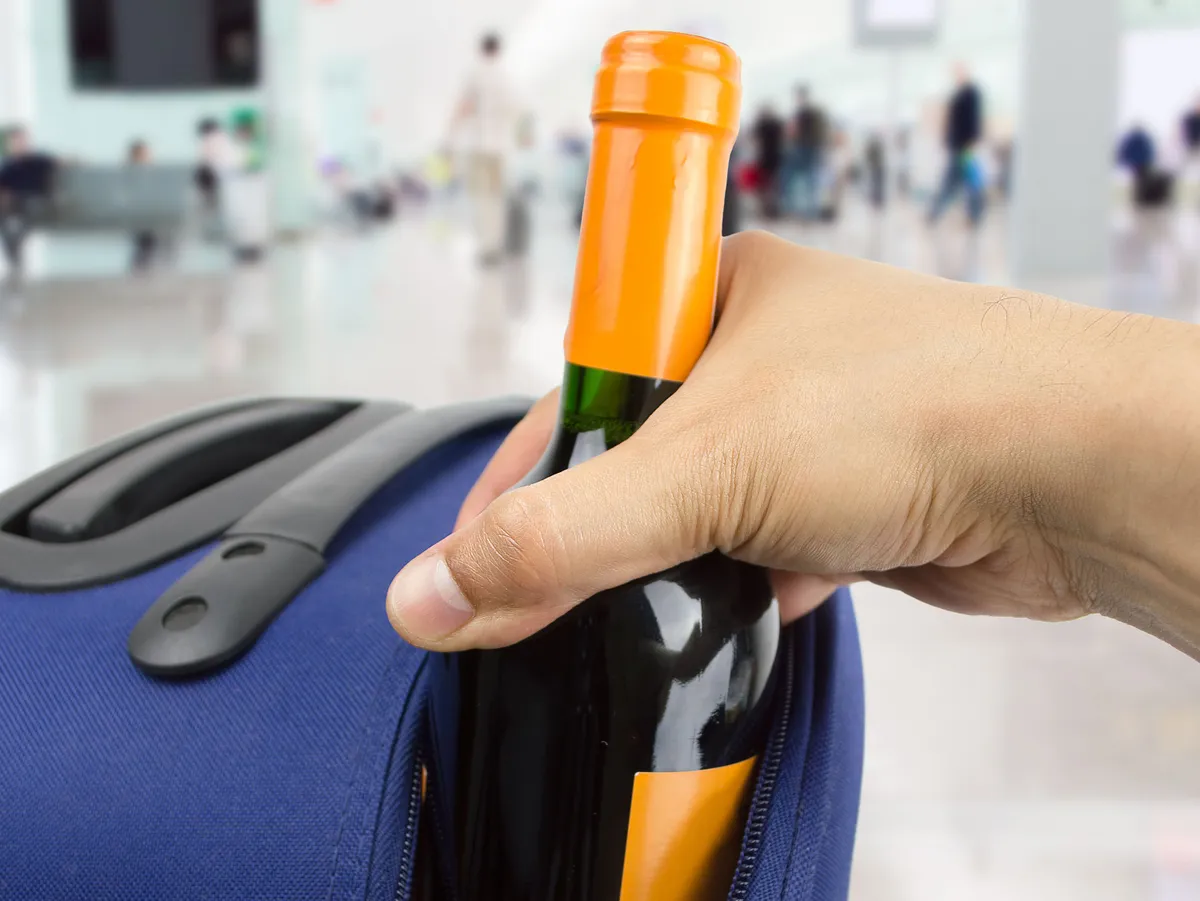 stealing wine bottle of a suitcase at the airport
