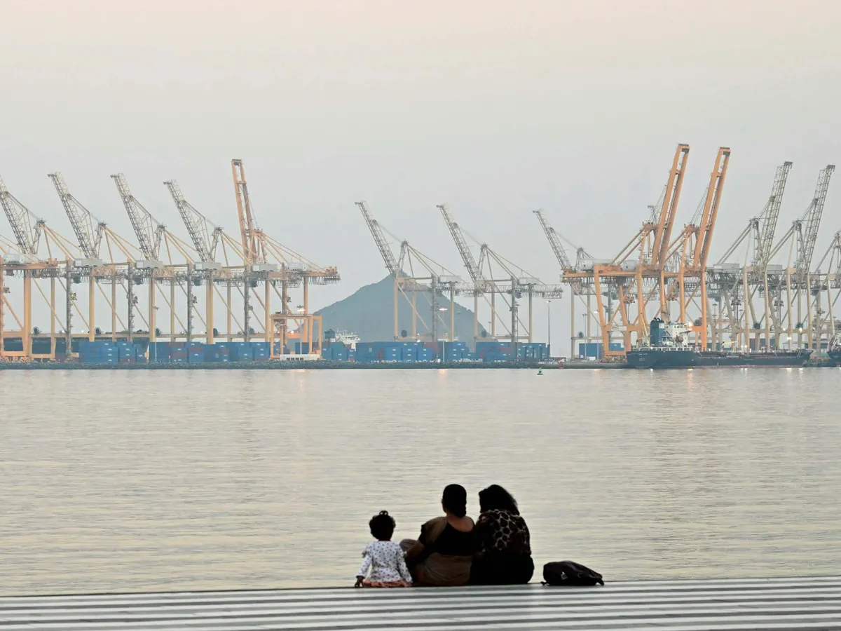 Hormuzi-szoros, hajózás, Hormuzi-szoroshajózás, 

A family sits against the backdrop of a dockyard off coast city of Fujairah, in the Strait of Hormuz in the northern Emirate on February 25, 2026. (Photo by Giuseppe CACACE / AFP)