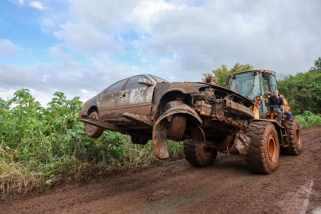 A destroyed car is moved off the road after the Kona Low storm flood devastated the Otake Camp community in Waialua, Hawaii, on March 22, 2026. Severe rains have battered the region over the weekend prompting officials to order evacuations. (Photo by Marco GARCIA / AFP)