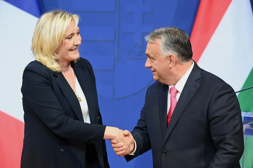 Leader of French far-right party Rassemblement National (RN) and candidate for the presidential elections Marine Le Pen (L) shakes hands with Hungarian Prime Minister Viktor Orban during their joint press conference in the Prime Ministers office, the Carmelita monastery of Buda castle district in Budapest, Hungary, on October 26, 2021. (Photo by Attila KISBENEDEK / AFP)