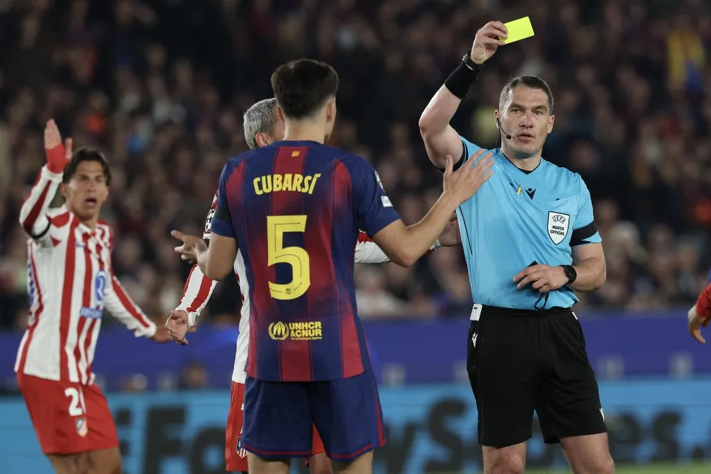 Barcelona's Spanish defender #05 Pau Cubarsi (L) is shown a yellow card from Romanian referee Istvan Kovacs during the UEFA Champions League quarter final first leg football match between FC Barcelona and Club Atletico de Madrid at Camp Nou Stadium in Barcelona on April 8, 2026. (Photo by Lluis GENE / AFP)