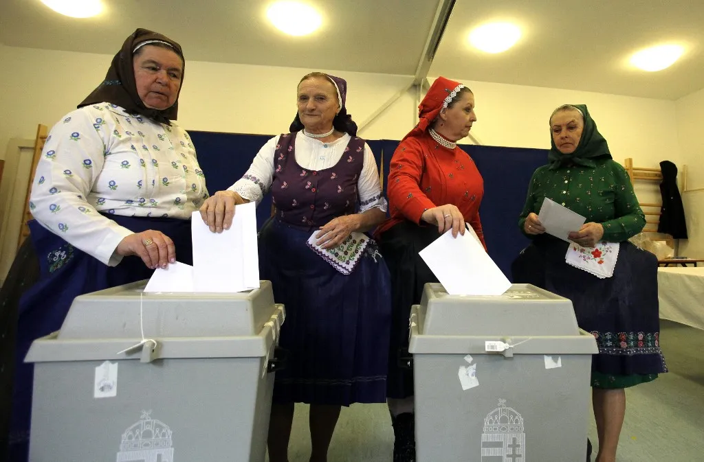Women in traditional Hungarian dresses cast their ballots at a polling station in a nursery school in Veresegyhaz, some 30km east of Budapest, on April 12, 2026, during the general election in Hungary. The vote could end Hungarian Prime Minister Viktor Orban's 16-year stint in power as the EU's longest serving current leader and a self-decribed "thorn" in the bloc's side. (Photo by Peter Kohalmi / AFP)