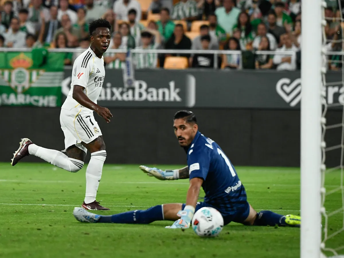 Real Madrid's Brazilian forward #07 Vinicius Junior (L) scores his team's first goal past Real Betis' Spanish goalkeeper #01 Alvaro Valles during the Spanish league football match between Real Betis and Real Madrid CF at the La Cartuja stadium in Seville on April 24 , 2026. (Photo by CRISTINA QUICLER / AFP)