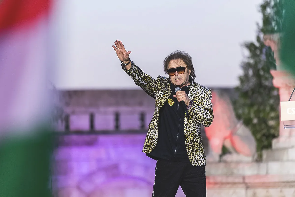 Szikora Róbert leopard mintas zakóban, mikrofonnal a kezében ad koncertet.