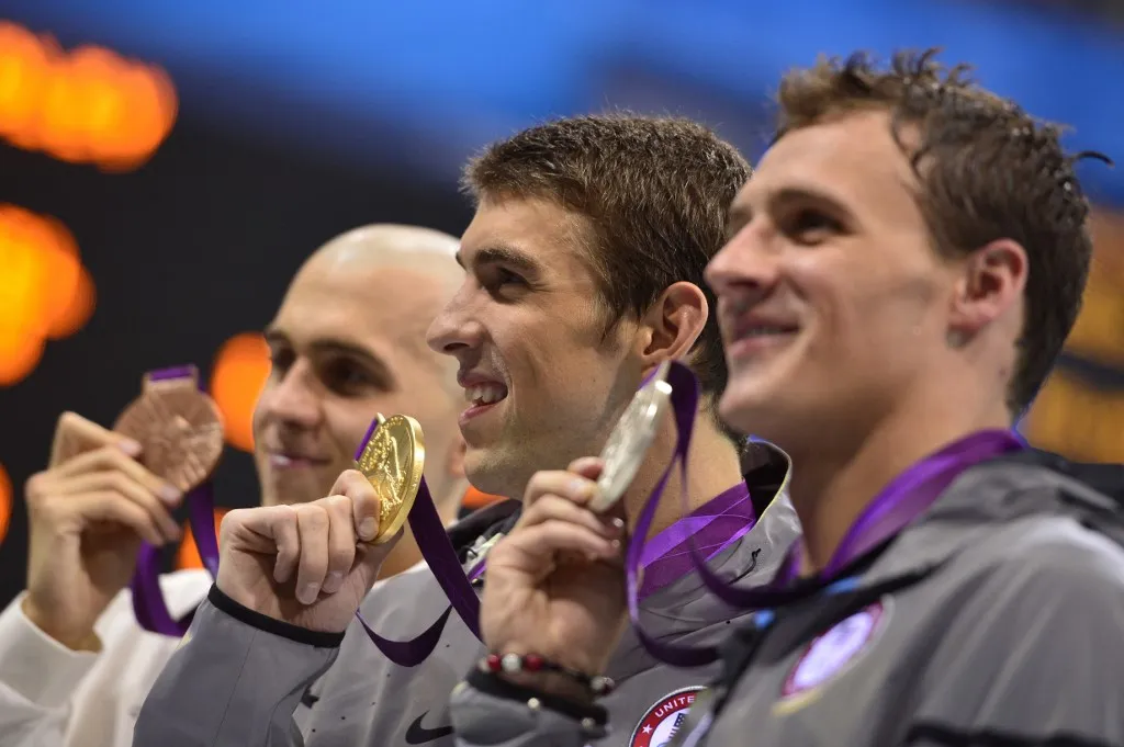 US swimmer Michael Phelps (C) poses on the podium with the gold medal flanked by silver medalist US swimmer Ryan Lochte (R) and bronze medalist Hungary's Laszlo Cseh (L) after winning the men's 200m individual medley swimming event at the London 2012 Olympic Games on August 2, 2012 in London. AFP PHOTO / FABRICE COFFRINI (Photo by FABRICE COFFRINI / AFP)