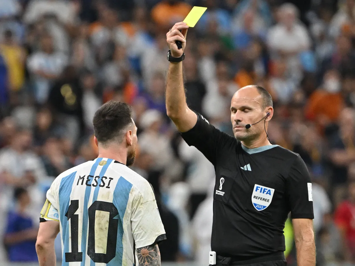 Spanish referee Antonio Mateu Lahoz shows a yellow card to Argentina's forward #10 Lionel Messi during the Qatar 2022 World Cup quarter-final football match between Netherlands and Argentina at Lusail Stadium, north of Doha, on December 9, 2022. (Photo by Alberto PIZZOLI / AFP)