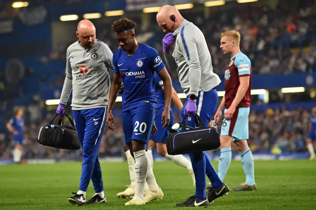 Chelsea's English midfielder Callum Hudson-Odoi (C) receives medical attention after picking up an injury during the English Premier League football match between Chelsea and Burnley at Stamford Bridge in London on April 22, 2019. (Photo by Glyn KIRK / AFP) / RESTRICTED TO EDITORIAL USE. No use with unauthorized audio, video, data, fixture lists, club/league logos or 'live' services. Online in-match use limited to 120 images. An additional 40 images may be used in extra time. No video emulation. Social media in-match use limited to 120 images. An additional 40 images may be used in extra time. No use in betting publications, games or single club/league/player publications. / 