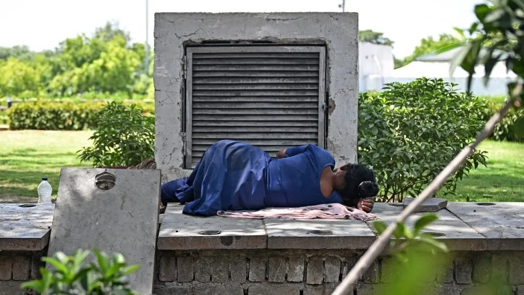 Hőségriasztás Indiában - A woman sleeps next to an air conditioner vent exuding cool air at a park on a hot summer afternoon in New Delhi on April 22, 2026. Weather forecasters predict temperatures will hit 41-43C in India's capital later on April 22, and rise to 42-44C later in the week. Summer heat in the world's most populous nation can be brutal -- putting millions of people at risk, with nearly 11,000 people dying due to heat stroke between 2012 and 2021, according to government data. (Photo by Sajjad HUSSAIN / AFP)