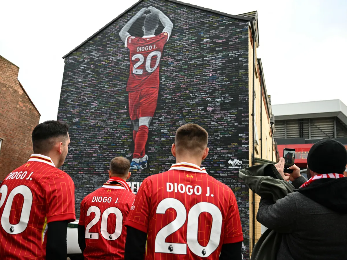 Fans visit a mural created by artist Murwalls, dedicated to Liverpool's late Portugese footballer Diogo Jota who died in a car crash in July, ahead of the English Premier League football match between Liverpool and Wolverhampton Wanderers at Anfield in Liverpool, north west England on December 27, 2025. Father of three Jota, who married his long-term partner Rute Cardoso 11 days before the accident, died alongside his brother after a Lamborghini they were travelling in came off the road and burst into flames in northern Spain in July. (Photo by Oli SCARFF / AFP) / RESTRICTED TO EDITORIAL USE - MANDATORY MENTION OF THE ARTIST UPON PUBLICATION - TO ILLUSTRATE THE EVENT AS SPECIFIED IN THE CAPTION
