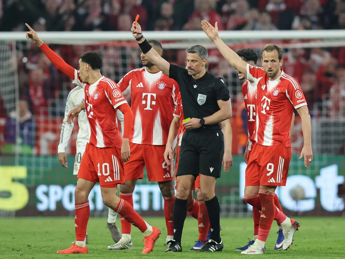 Real Madrid's French midfielder #06 Eduardo Camavinga (not in picture) is shown a red card by Slovenian referee Slavko Vincic as Bayern Munich's English forward #09 Harry Kane (R) and his teammates react during the UEFA Champions League quarter-final second leg football match between FC Bayern Munich and Real Madrid in Munich, southern Germany, on April 15, 2026. (Photo by Alexandra BEIER / AFP)