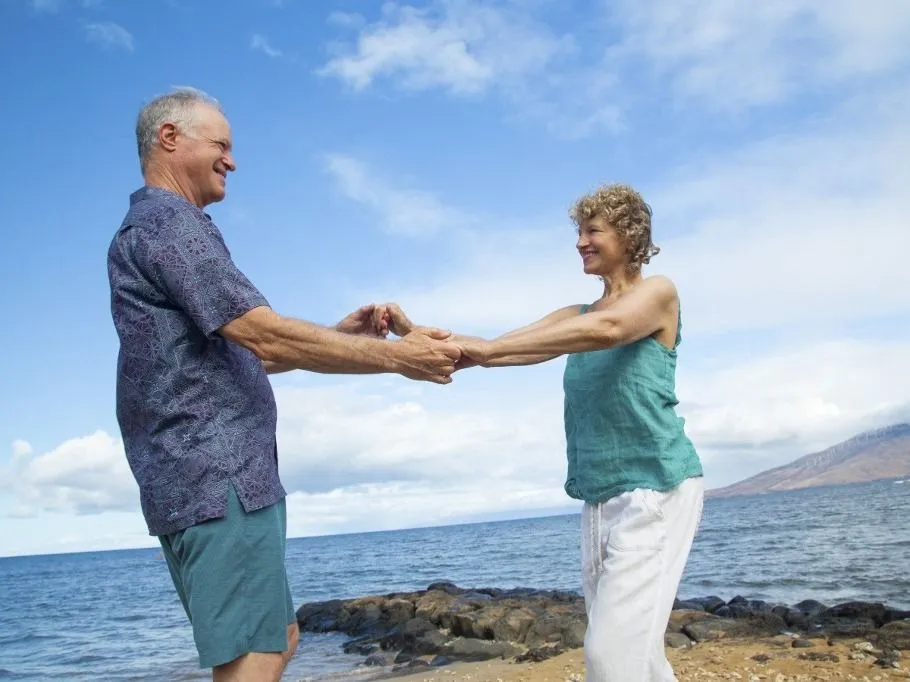 öregedés Elderly couple holding hands joyfully on a rocky ocean shore under a clear blue sky. Kepaniwai Park, Wailuku, Hawaii (Photo by Kicka / Connect Images via AFP)