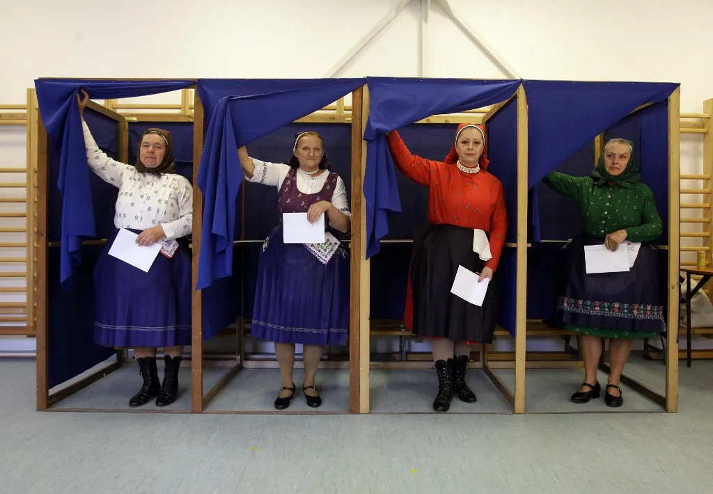 Women in traditional Hungarian dresses fill out their ballot papers at a polling station in a nursery school in Veresegyhaz, some 30km east of Budapest, on April 12, 2026, during the general election in Hungary. The vote could end Hungarian Prime Minister Viktor Orban's 16-year stint in power as the EU's longest serving current leader and a self-decribed "thorn" in the bloc's side. (Photo by Peter Kohalmi / AFP)