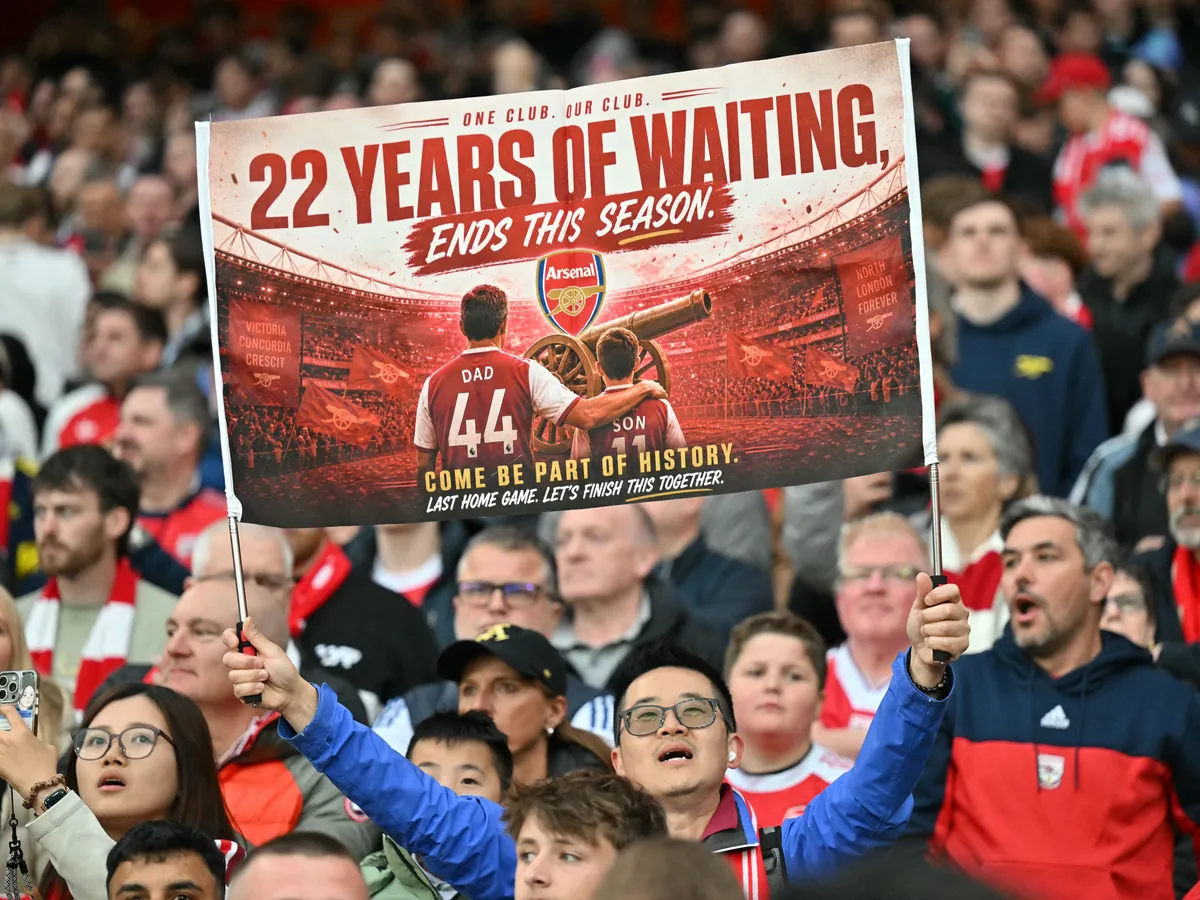 A hopeful Arsenal fan holds up a banner reading 22 years of waiting ends this season, during the English Premier League football match between Arsenal and Burnley at the Emirates Stadium in London on May 18, 2026. (Photo by Glyn KIRK / AFP) / RESTRICTED TO EDITORIAL USE. No use with unauthorized audio, video, data, fixture lists, club/league logos or 'live' services. Online in-match use limited to 120 images. An additional 40 images may be used in extra time. No video emulation. Social media in-match use limited to 120 images. An additional 40 images may be used in extra time. No use in betting publications, games or single club/league/player publications. / 