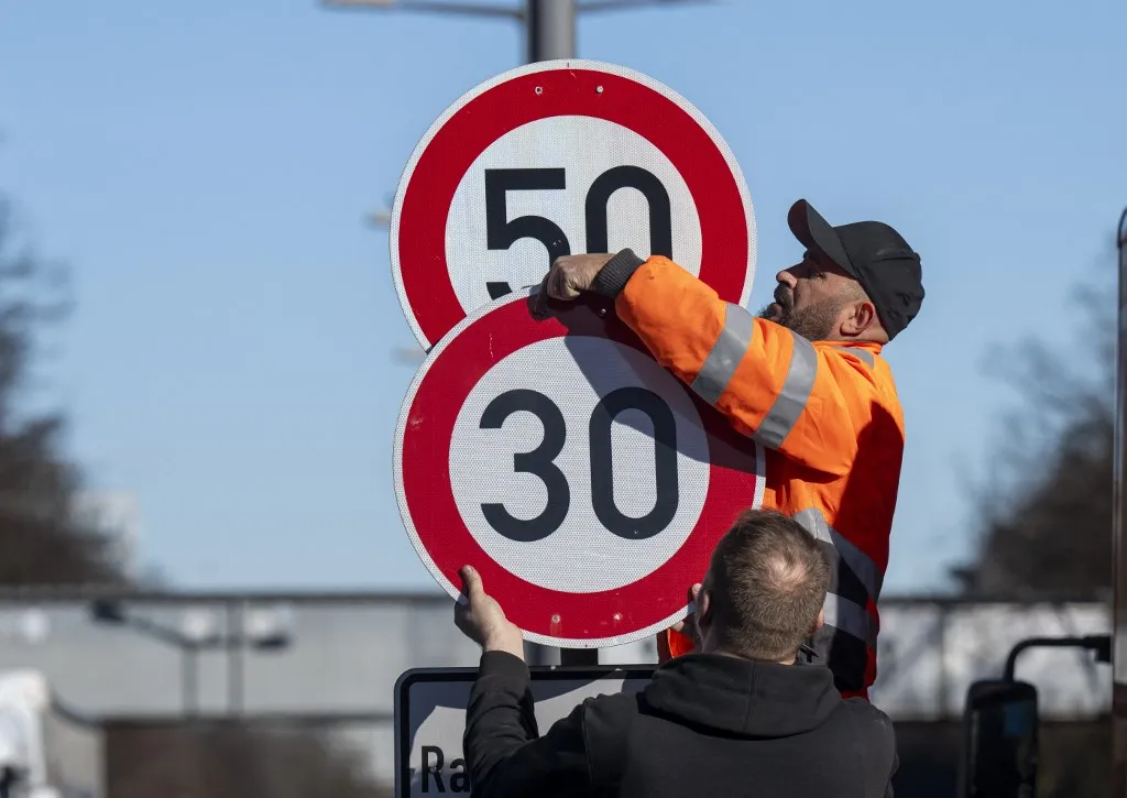 25 February 2026, Bavaria, Munich: Workers install a 30 km/h speed limit sign on Landshuter Allee. This means that the speed limit on this section of the Mittlerer Ring is now back to 30 kilometers per hour. Photo: Peter Kneffel/dpa (Photo by PETER KNEFFEL / dpa Picture-Alliance via AFP), Sok helyen változott a sebességhatár, ezért az autósoknak figyelniük kell