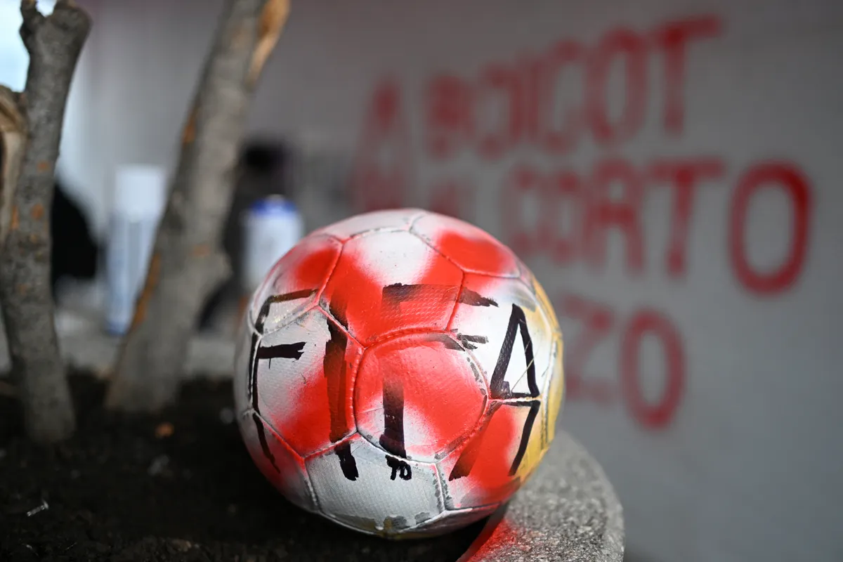 An Anti-FIFA World Cup activist paints an X on a ball that reads FIFA during a protest outside the Azteca stadium that will host the opening ceremony of the World Cup in Mexico City on May 27, 2026. Mexico will co-host the biggest World Cup in history along with the United States and Canada from June 11 to July 19, 2026. (Photo by Yuri CORTEZ / AFP)