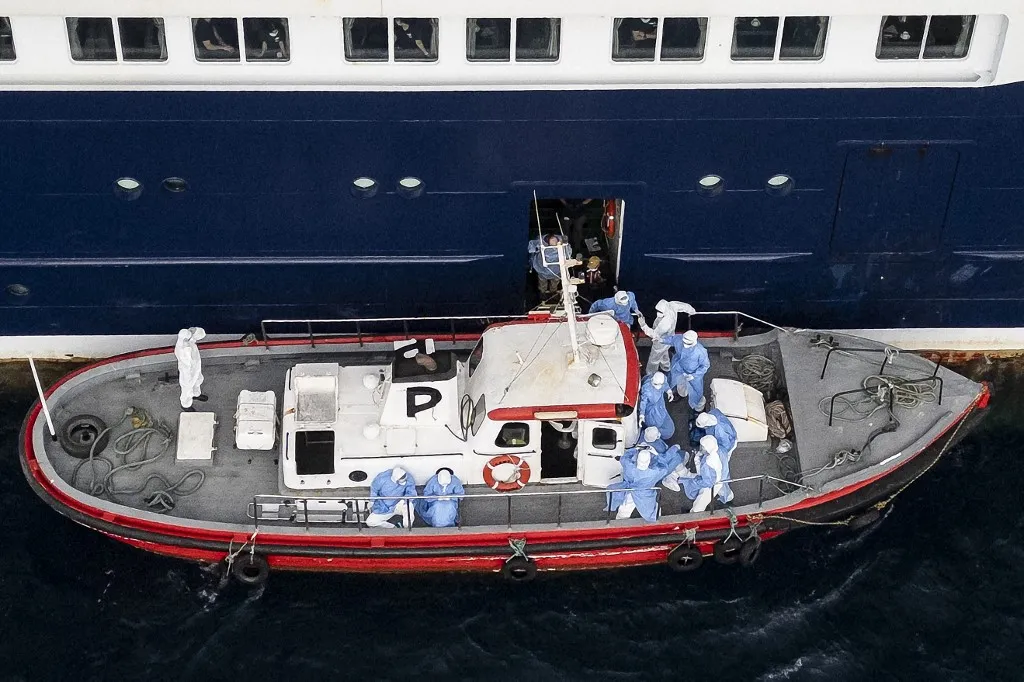 Hantavírus miatt evakuálták az óceánjáró betegeit Hollandiába - This aerial view shows health personnel assisting patients onto a boat from the cruise ship MV Hondius, while stationary off the port of Praia, the capital of Cape Verde, on May 6, 2026. Evacuations were taking place on May 6, 2026 from a cruise ship stricken with a deadly outbreak of hantavirus, the World Health Organization said, as experts confirmed a rare strain that can be transmitted between humans.Three people, two crew members and one other person, thought to be infected with the virus were being taken off the MV Hondius, anchored off Cape Verde, the WHO said. (Photo by AFP)