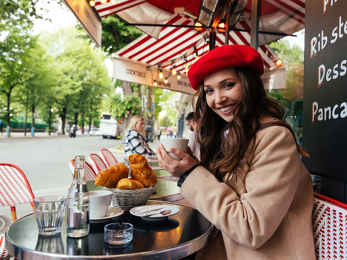 Beautiful young woman visiting paris and the eiffel tower. Parisian girl with red hat and fashionable clothes having fun in the city center and landmarks area