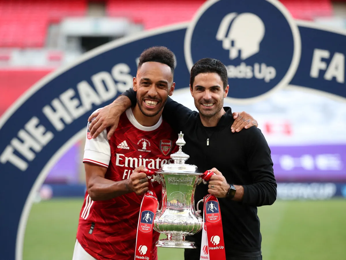 Arsenal's Gabonese striker Pierre-Emerick Aubameyang (L) and Arsenal's Spanish head coach Mikel Arteta hold the winner's trophy as the team celebrates victory after the English FA Cup final football match between Arsenal and Chelsea at Wembley Stadium in London, on August 1, 2020. Arsenal won the match 2-1. (Photo by Adam Davy / POOL / AFP) / NOT FOR MARKETING OR ADVERTISING USE / RESTRICTED TO EDITORIAL USE