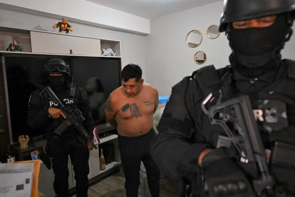 Egy rendőrségi akció során őrizetbe veszik a Los Lobos banda egyik vezetőjét egy hajnali razzia során Quitóban, 2026. május 14-én, Ecuadorban, Police arrest Eduardo Gomez, alias "Gordo Paul", a leader of Los Lobos drug trafficking group, during a curfew imposed by Ecuador's President Daniel Noboa to tackle organized crime, in Quito in the early hours of May 14, 2026. Ecuador's police on May 14 captured a "dangerous" leader of Los Lobos, the country's largest drug trafficking group, in a cinematic operation led by Interior Minister Jhon Reimberg, AFP reporters witnessed. (Photo by AFP)