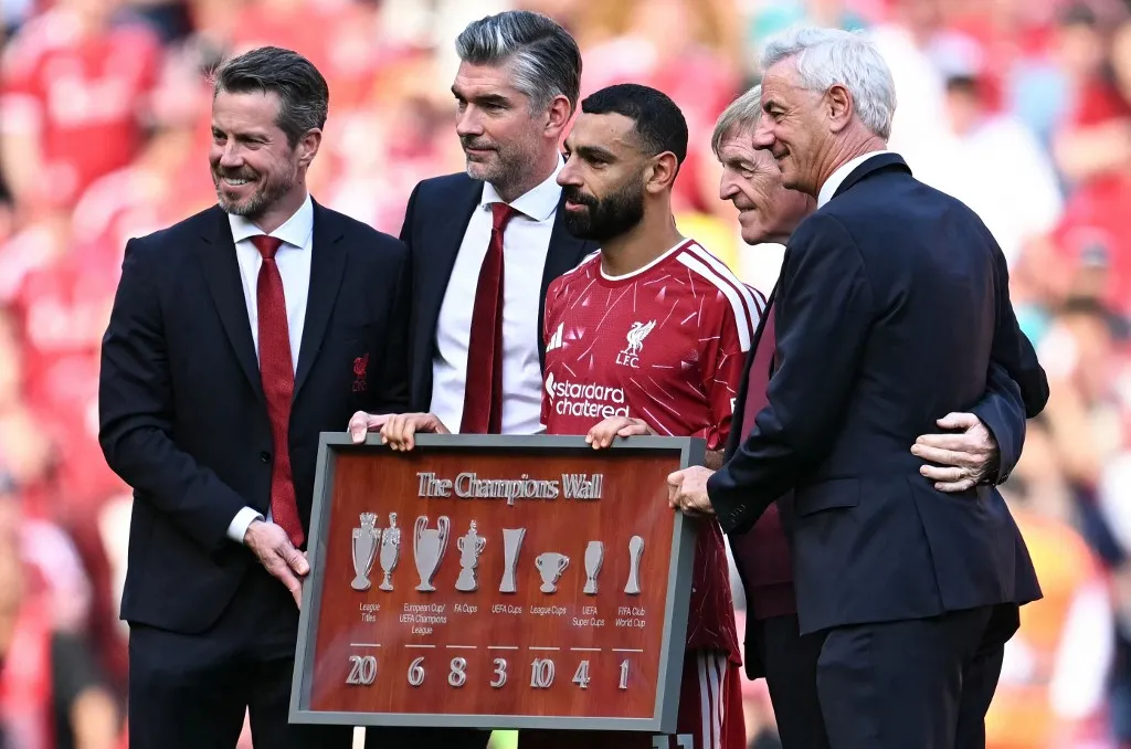 Liverpool's Egyptian striker #11 Mohamed Salah (C) is given "The Champions Wall" framed trophy gift after the English Premier League football match between Liverpool and Brentford at Anfield in Liverpool, north west England on May 24, 2026. (Photo by Paul ELLIS / AFP) / RESTRICTED TO EDITORIAL USE. No use with unauthorized audio, video, data, fixture lists, club/league logos or 'live' services. Online in-match use limited to 120 images. An additional 40 images may be used in extra time. No video emulation. Social media in-match use limited to 120 images. An additional 40 images may be used in extra time. No use in betting publications, games or single club/league/player publications. / 