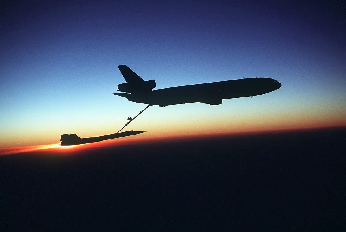 A right side view of a KC-10 Extender aircraft refueling an SR-71 Blackbird aircraft in-flight during testing.  The Extender, silhouetted against the sunset horizon, is from the 78th Air Refueling Squadron, and the Blackbird, the 9th Strategic Reconnaissance Wing.