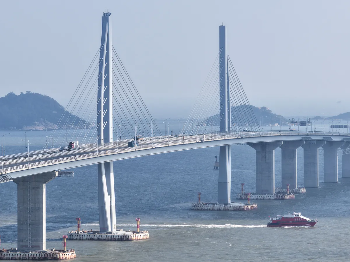 (251022) -- GUANGZHOU, Oct. 22, 2025 (Xinhua) -- An aerial drone photo taken on Oct. 19, 2025 shows cruise ships passing under the Hong Kong-Zhuhai-Macao Bridge in south China. More than 93.34 million inbound and outbound passenger trips had been recorded through the Zhuhai port of the Hong Kong-Zhuhai-Macao Bridge as of Wednesday, seven years after the bridge opened to traffic.
  According to the bridge's border inspection station, they handled 12.88 million passenger trips in 2019 and 860,000 vehicle trips that year. These numbers rose to 27 million and 5.55 million, respectively, in 2024 -- and have exceeded 25.1 million and 5.46 million, respectively, so far this year, up 17 and 25 percent year on year, respectively. (Xinhua/Deng Hua) (Photo by Deng Hua / Xinhua via AFP)